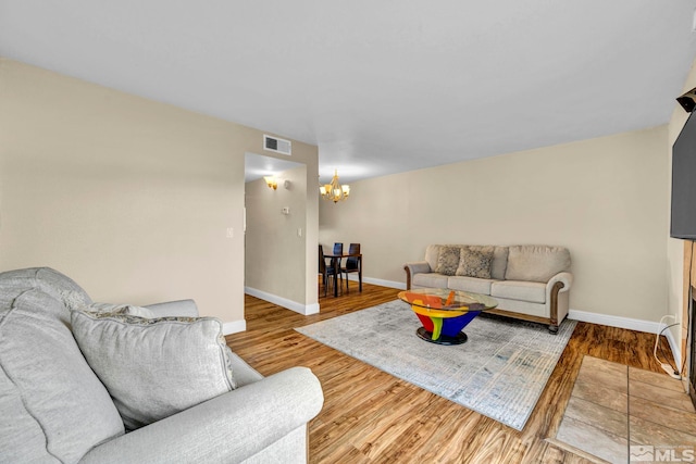 living room with an inviting chandelier, wood finished floors, visible vents, and baseboards