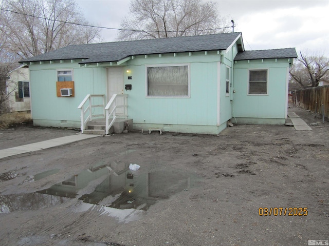 view of front of property with crawl space, roof with shingles, and fence