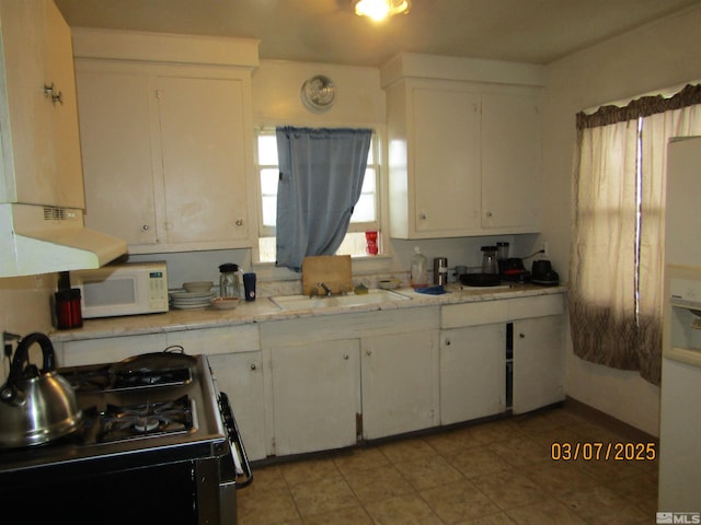 kitchen with range hood, gas stove, white microwave, a sink, and white cabinets