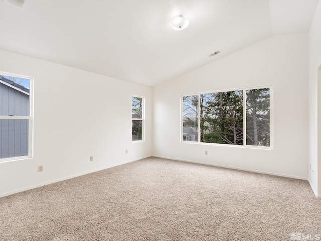 carpeted spare room featuring lofted ceiling, baseboards, and visible vents