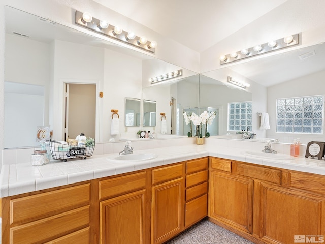 bathroom with double vanity, visible vents, and a sink