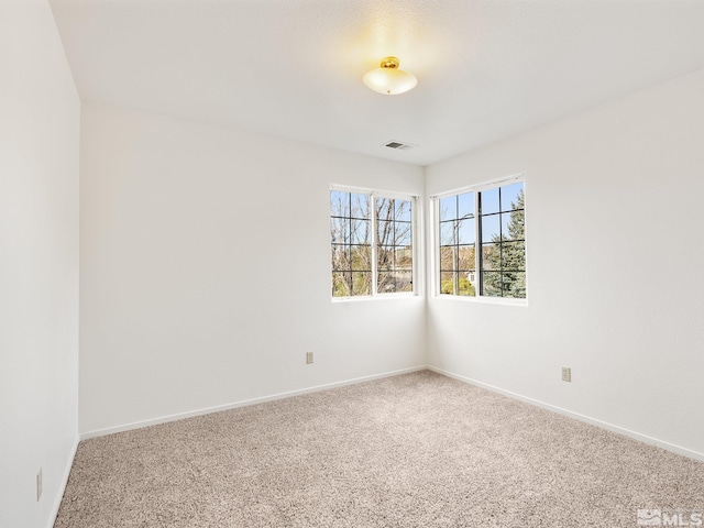 carpeted empty room featuring baseboards and visible vents