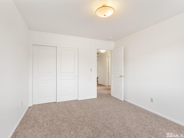 unfurnished bedroom with a closet, baseboards, and light colored carpet