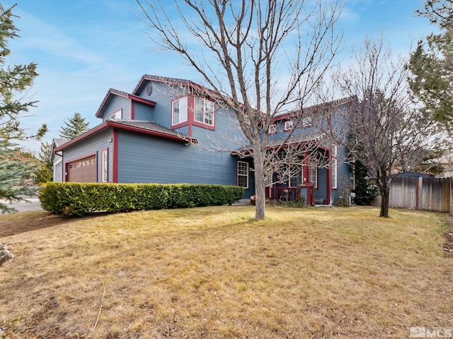 view of front facade featuring a front yard, an attached garage, and fence