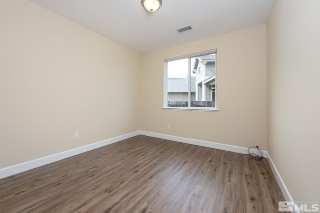 unfurnished room featuring visible vents, baseboards, and wood finished floors