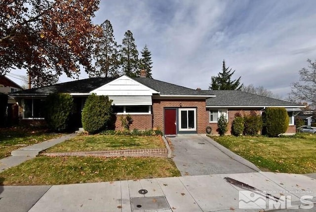 view of front of property with brick siding, a front lawn, and a shingled roof