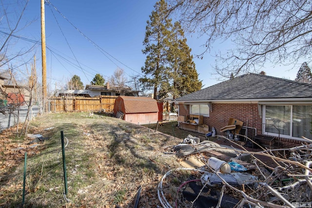 view of yard featuring an outdoor structure, fence, and a shed