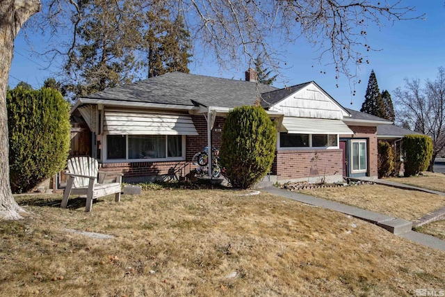 view of front of house with a front yard, brick siding, roof with shingles, and a chimney