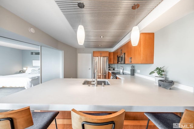 kitchen featuring brown cabinets, a breakfast bar, a sink, stainless steel appliances, and a peninsula