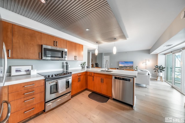 kitchen with light countertops, light wood-type flooring, appliances with stainless steel finishes, and a sink