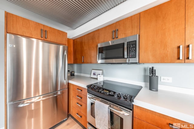 kitchen featuring appliances with stainless steel finishes, brown cabinetry, and light countertops