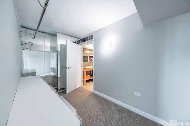 hall featuring baseboards and carpet floors