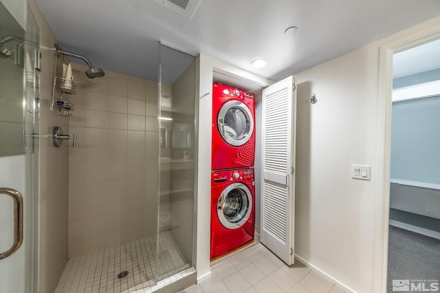 washroom with light tile patterned floors, stacked washer and clothes dryer, and laundry area