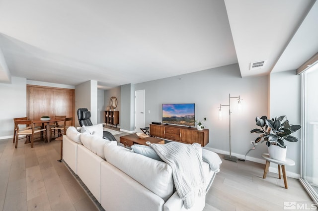 living area featuring baseboards, visible vents, and light wood finished floors