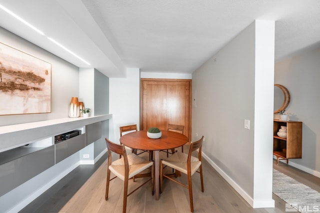 dining area featuring light wood finished floors and baseboards