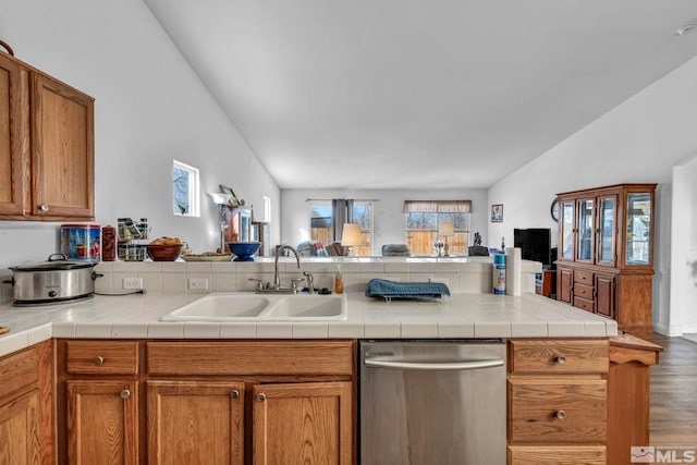 kitchen featuring open floor plan, dishwasher, vaulted ceiling, wood finished floors, and a sink