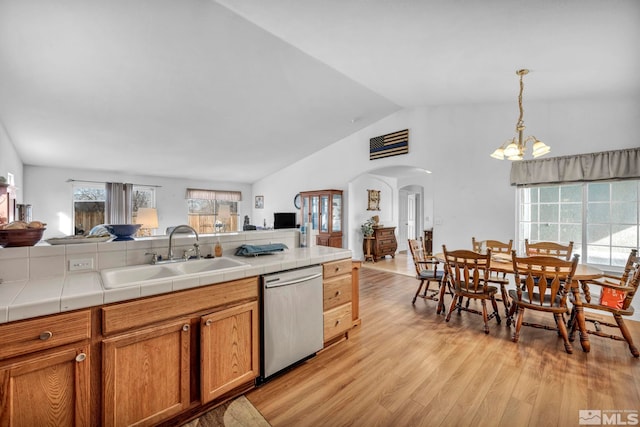 kitchen with arched walkways, a sink, open floor plan, dishwasher, and light wood-type flooring