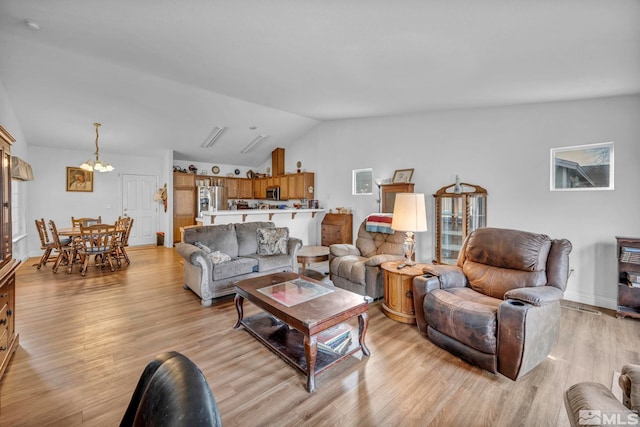 living room featuring light wood finished floors, baseboards, and vaulted ceiling