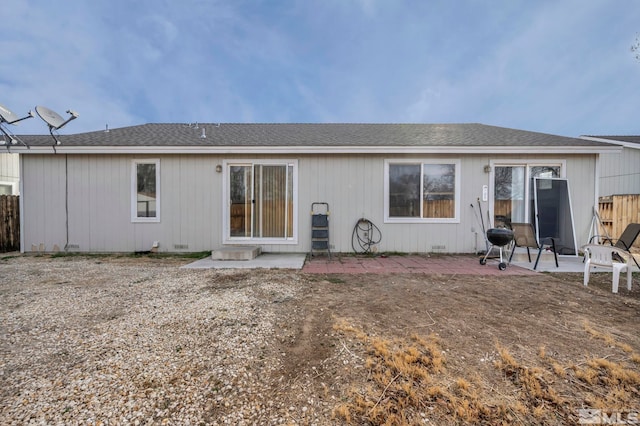 rear view of house featuring crawl space, fence, a shingled roof, and a patio area