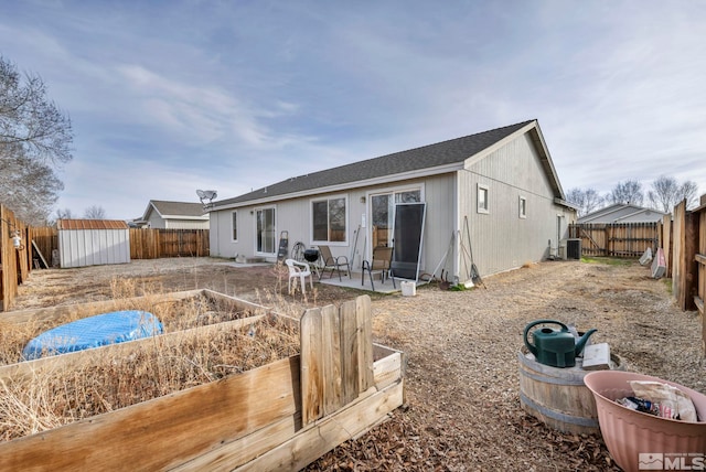 back of property with a storage shed, an outdoor structure, a fenced backyard, and a patio