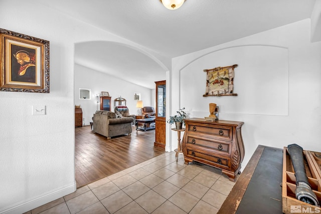 interior space with tile patterned floors, arched walkways, and lofted ceiling