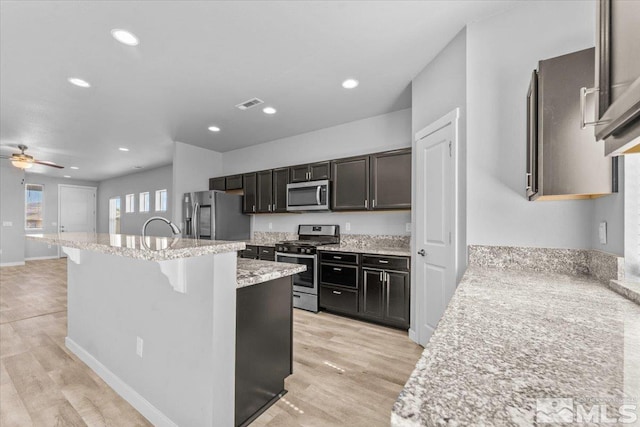 kitchen with visible vents, a center island with sink, stainless steel appliances, and light wood-type flooring