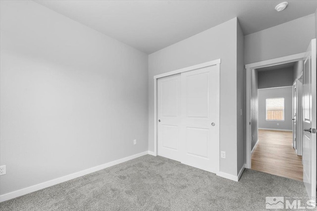 unfurnished bedroom featuring a closet, baseboards, and carpet