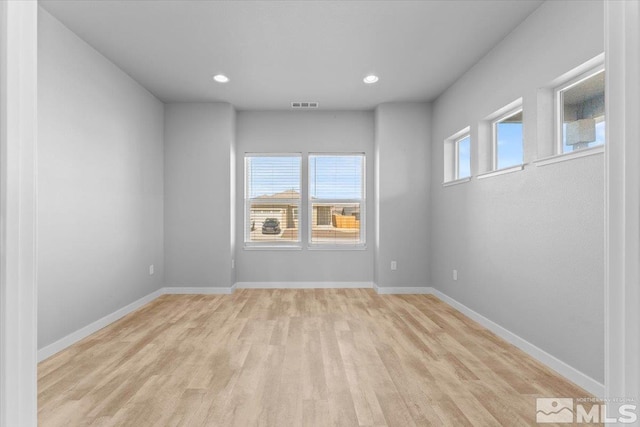 unfurnished room with visible vents, a healthy amount of sunlight, light wood-style floors, and baseboards