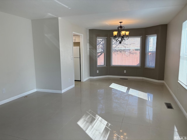 tiled spare room with baseboards, visible vents, a wealth of natural light, and a chandelier