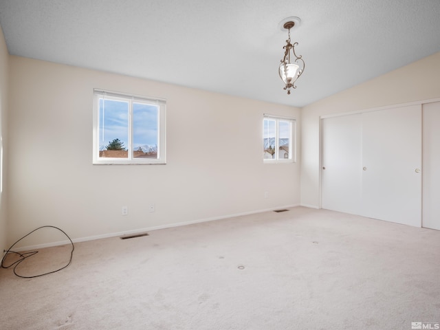 unfurnished bedroom with visible vents, carpet floors, lofted ceiling, and a closet