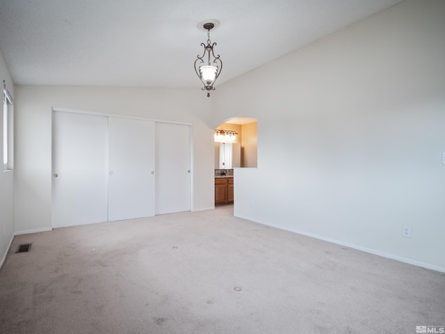 unfurnished bedroom featuring visible vents, baseboards, a closet, light carpet, and arched walkways