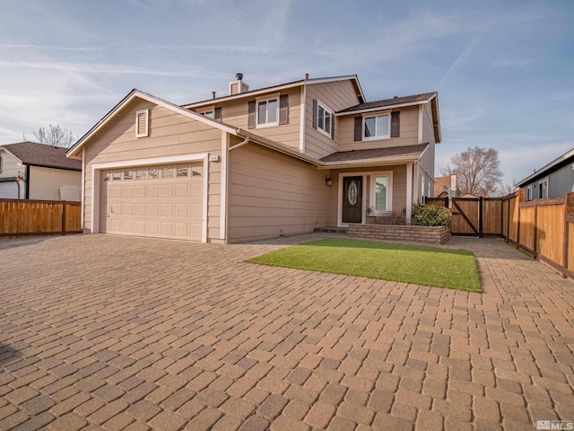 traditional home featuring decorative driveway, fence, an attached garage, and a gate