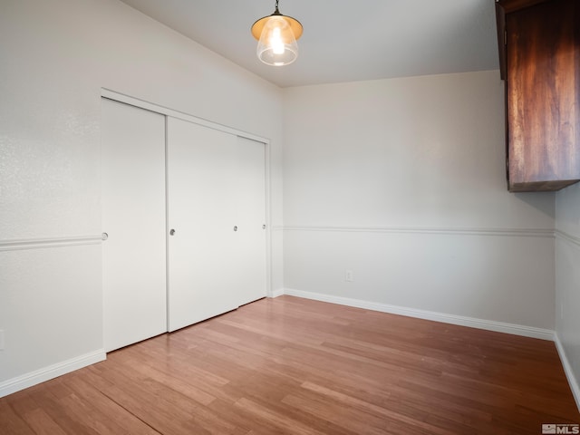 unfurnished bedroom featuring light wood-style floors, a closet, and baseboards