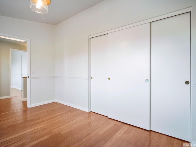 unfurnished bedroom with a closet, baseboards, and light wood-style flooring