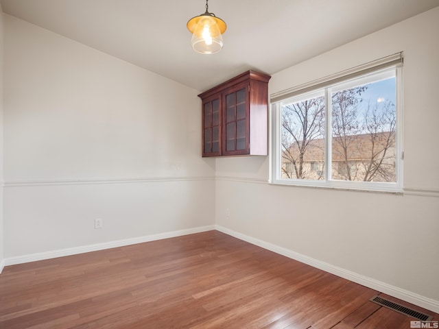 empty room with visible vents, baseboards, and wood finished floors