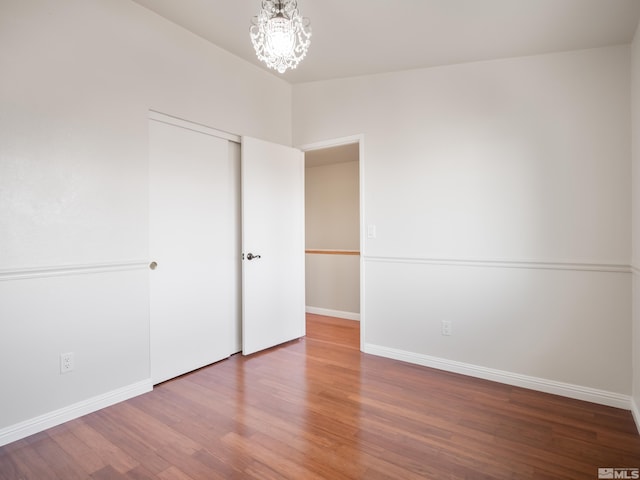 unfurnished bedroom featuring a closet, baseboards, wood finished floors, and vaulted ceiling