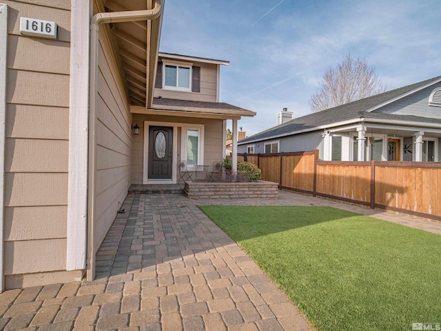 entrance to property featuring a yard and fence