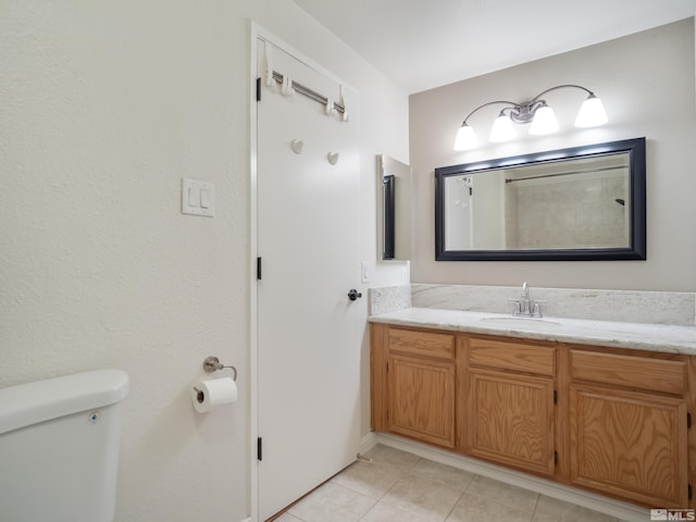 bathroom with toilet, vanity, and tile patterned flooring