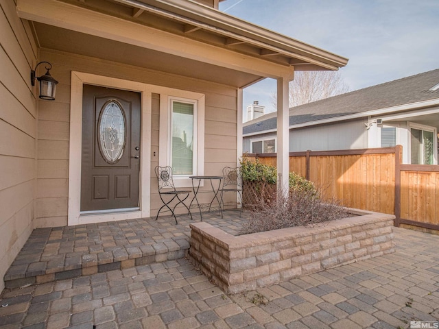 view of exterior entry featuring a porch and fence