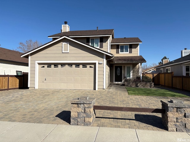 traditional-style house with an attached garage, a chimney, decorative driveway, and fence