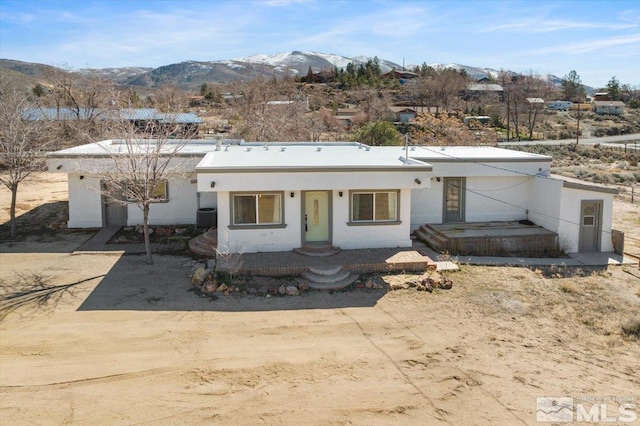 view of front facade with a mountain view, cooling unit, and stucco siding