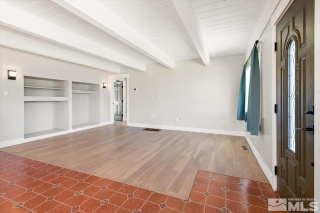 unfurnished living room featuring built in features, baseboards, visible vents, beam ceiling, and tile patterned flooring