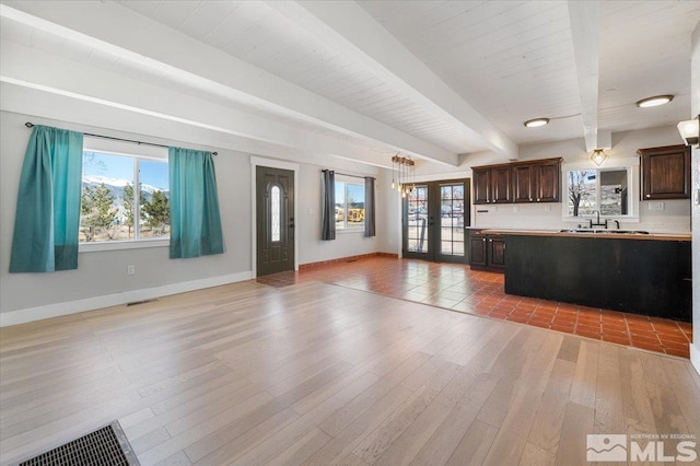 kitchen featuring visible vents, dark brown cabinets, beamed ceiling, open floor plan, and french doors