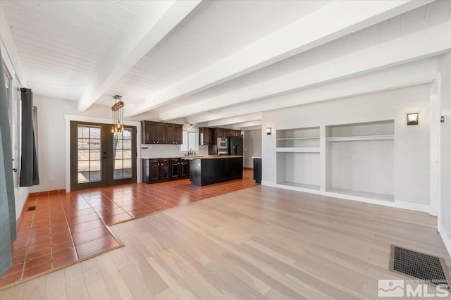 unfurnished living room with visible vents, beamed ceiling, french doors, and light wood-style flooring