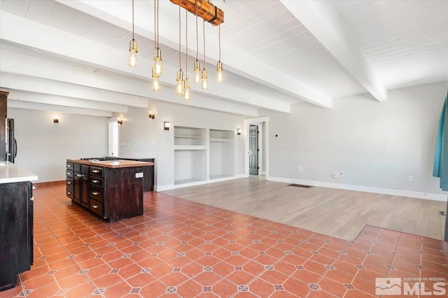 kitchen featuring beamed ceiling, built in features, baseboards, dark brown cabinets, and hanging light fixtures