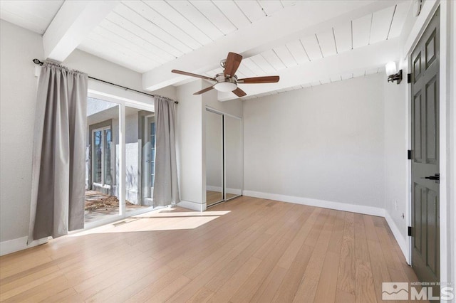 unfurnished room with beamed ceiling, a ceiling fan, light wood-style floors, and baseboards