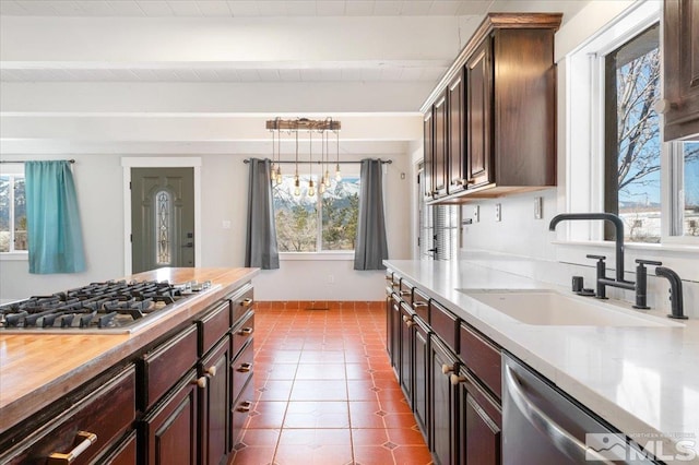 kitchen featuring a sink, dark brown cabinetry, appliances with stainless steel finishes, tile patterned flooring, and light countertops