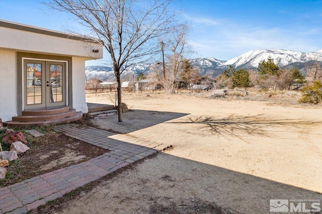 view of yard with french doors and a mountain view