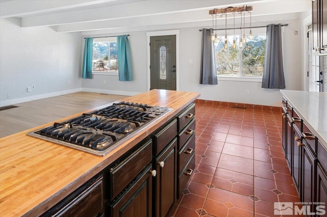 kitchen with butcher block counters, dark tile patterned floors, baseboards, and stainless steel gas cooktop