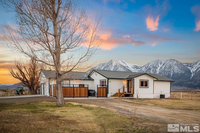 view of front of house with metal roof, driveway, a lawn, and a mountain view